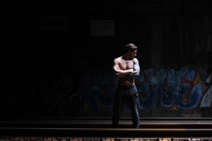 man topless posing on train tracks, levi