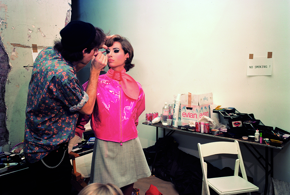 isaac mizrahi fashion, model backstage in pink jacket getting makeup done