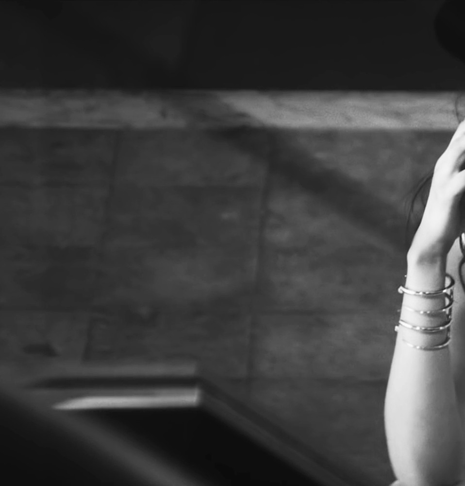 bella hadid posing with hand on face and wearing a black hat