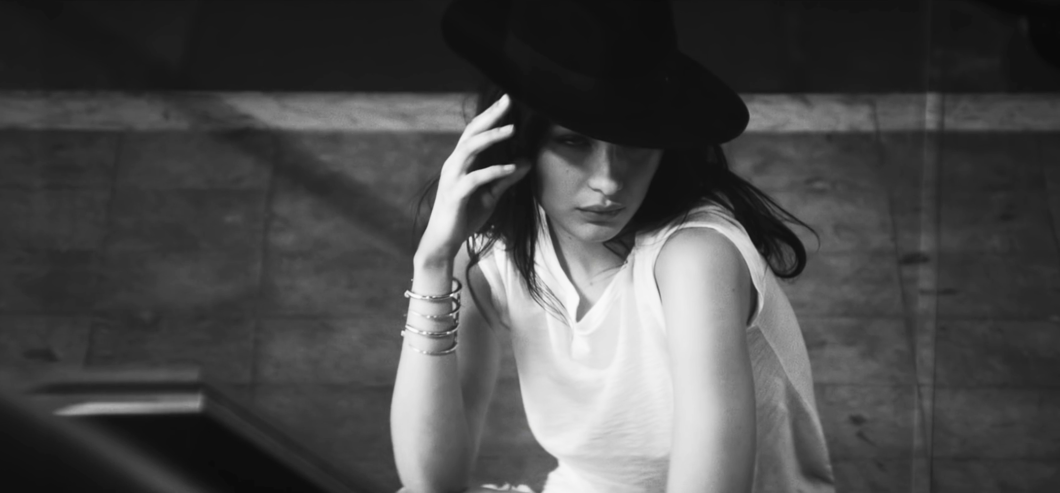 bella hadid posing with hand on face and wearing a black hat