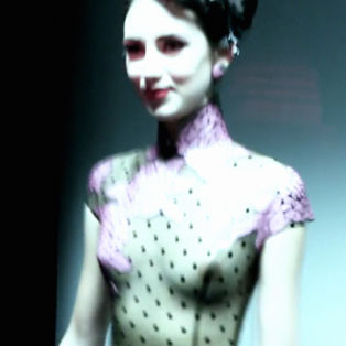 Atsuko Kudo's Lingerie London show, backstage shot of a model in latex corset with breasts exposed