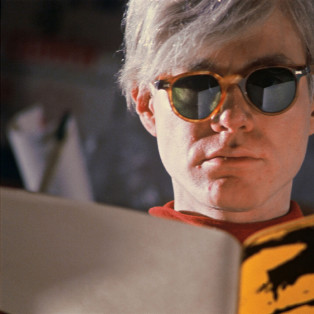 andy warhol wearing glasses and reading a book