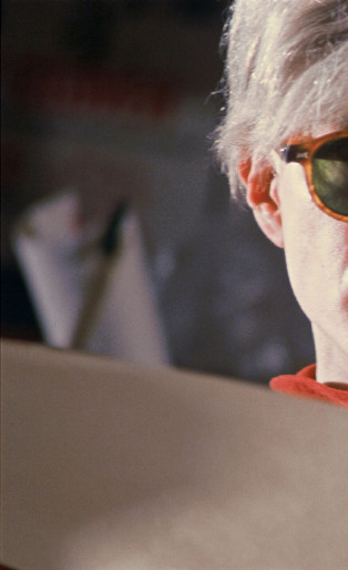 andy warhol wearing glasses and reading a book