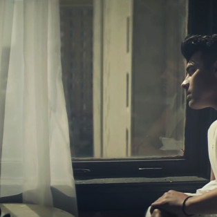 joe jonas staring out a window while wearing a sleeveless t shirt