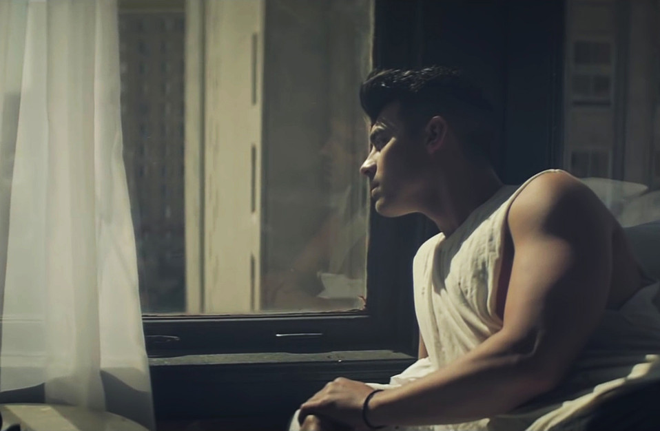 joe jonas staring out a window while wearing a sleeveless t shirt