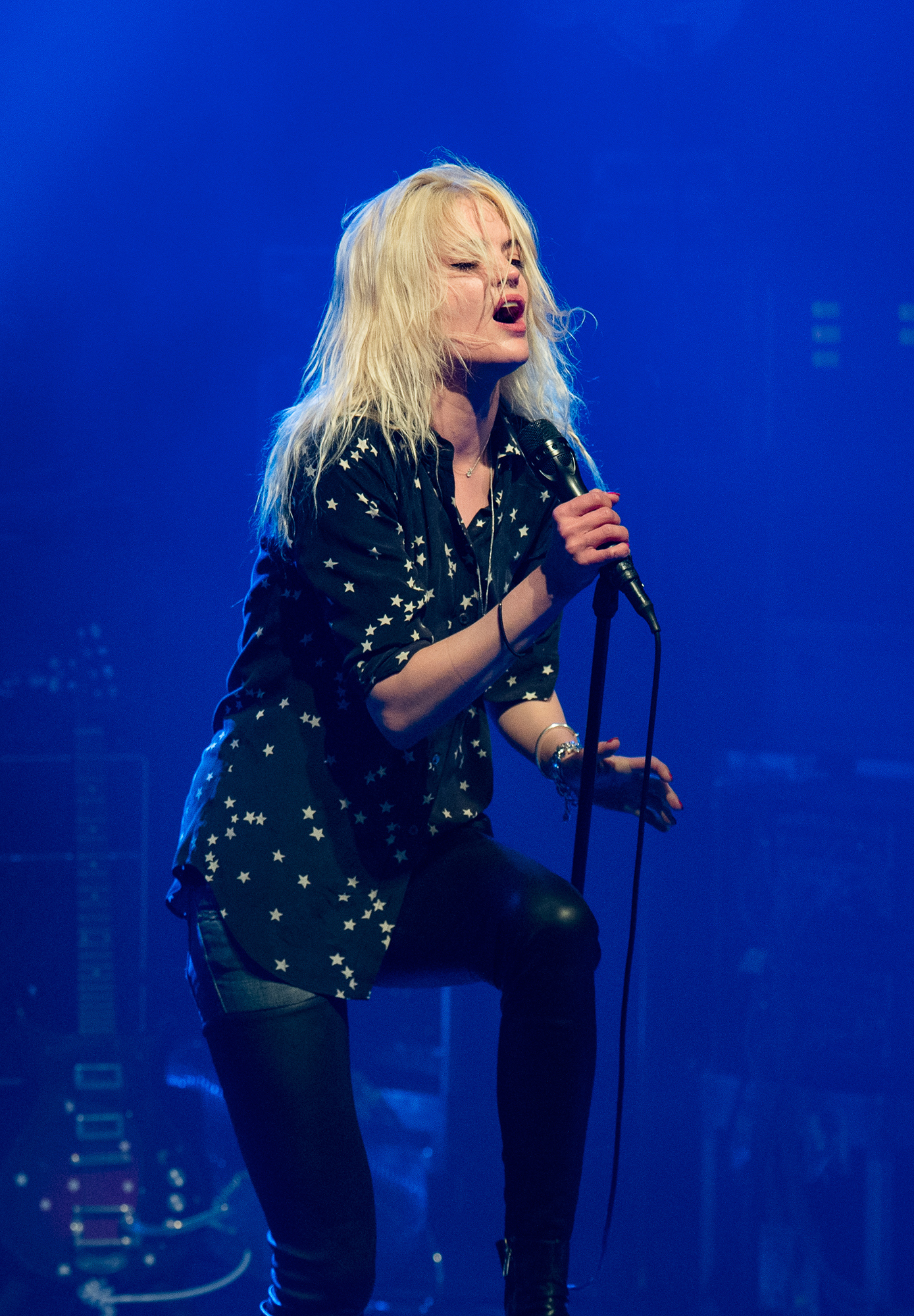 Alison Mosshart of The Kills wearing a star shirt and singing and performing on stage