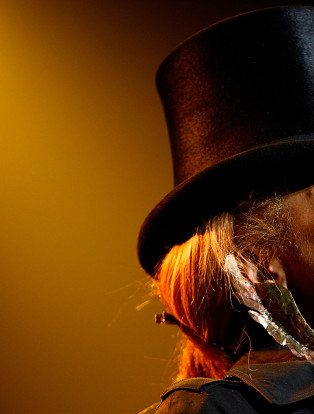 female performer singing into a microphone and wearing a top hat