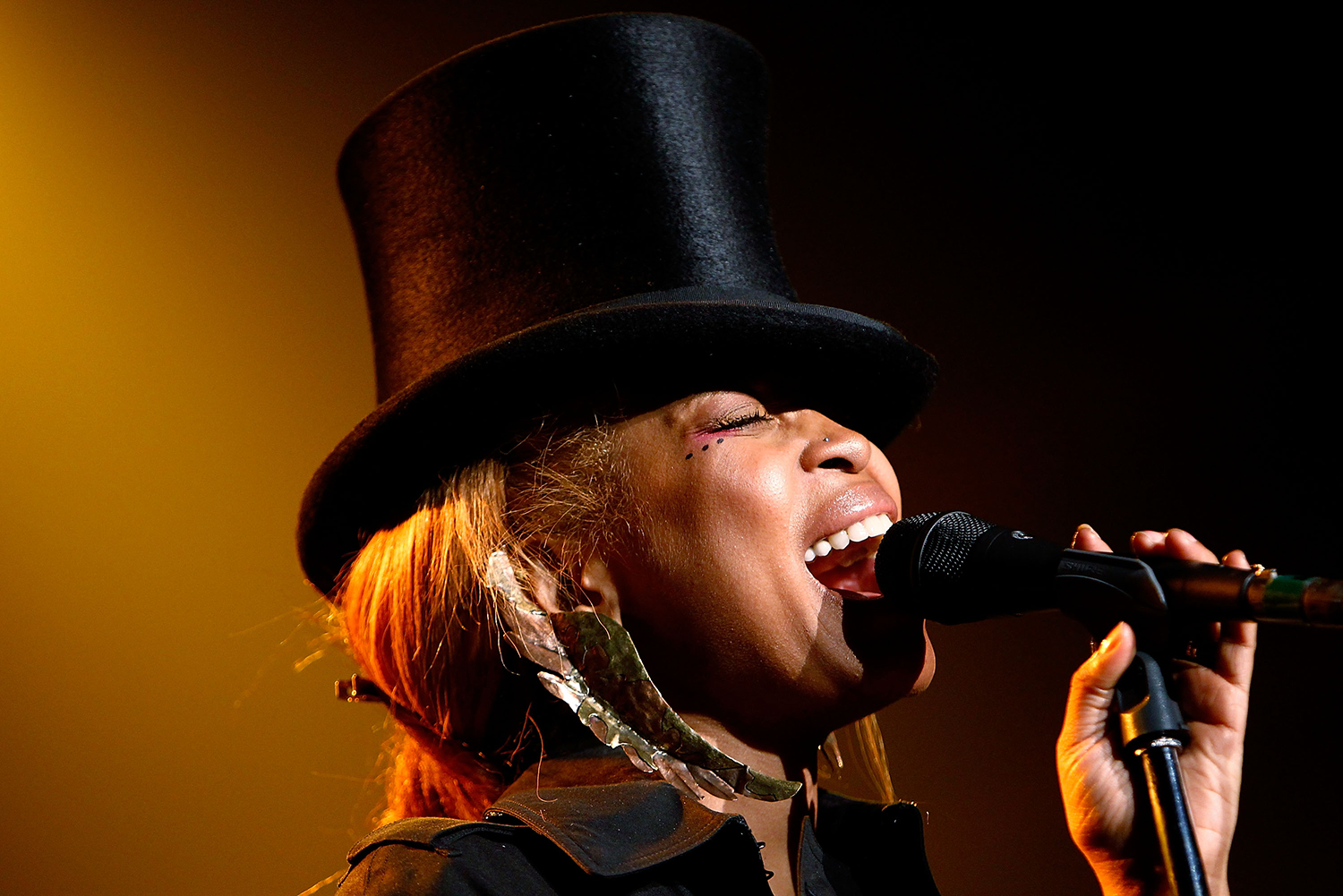 female performer singing into a microphone and wearing a top hat