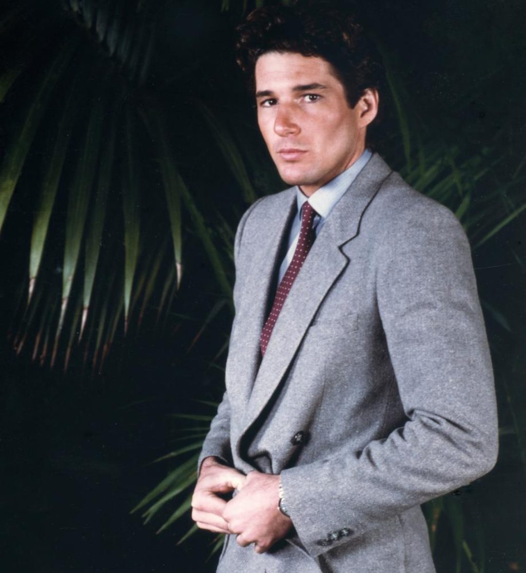 Richard Gere in his twenties looking handsome wearing a gray suit