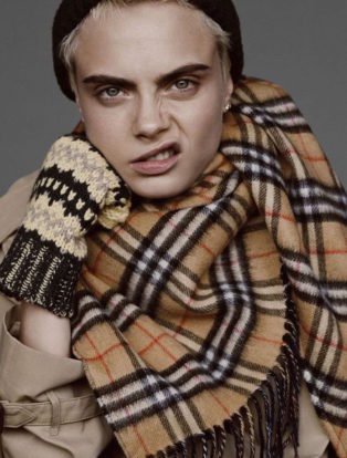 Cara Delevigne wearing a burberry scarf and snarling at the camera