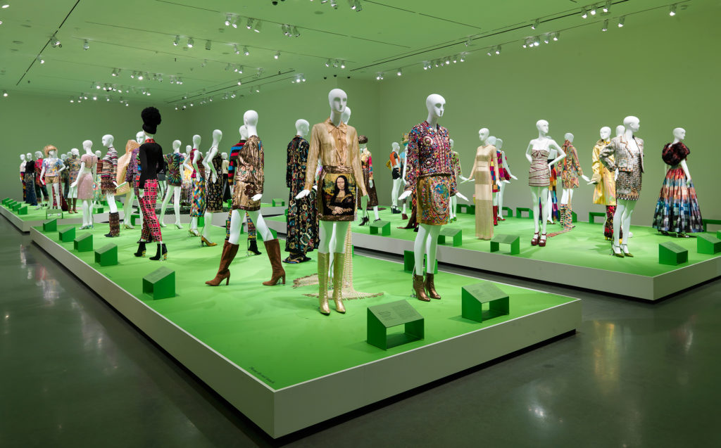 Photograph of mannequin models displayed on two green platforms at the Todd Oldham exhibition at the Wexner Center for the Arts