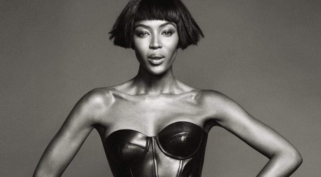 Black and white photograph of Naomi Campbell wearing a black leather bustier