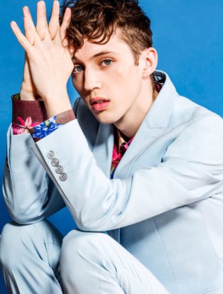 Troy Sivan white suit sitting elbows on knees