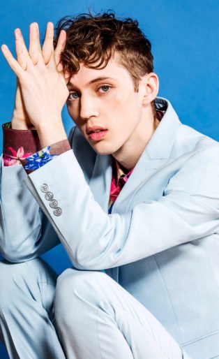 Troy Sivan white suit sitting elbows on knees