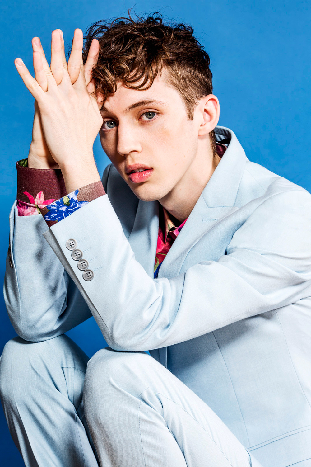 Troy Sivan white suit sitting elbows on knees