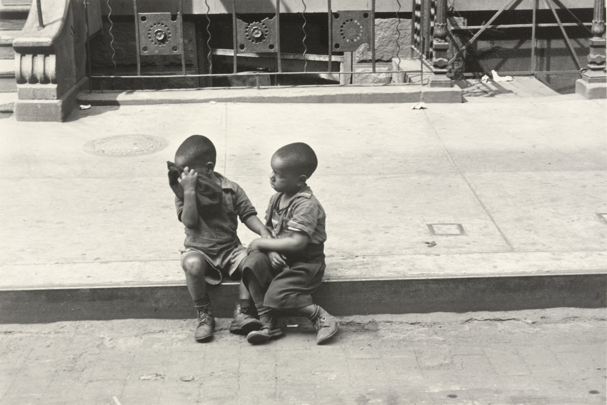 Two boys sitting on a curb in New York