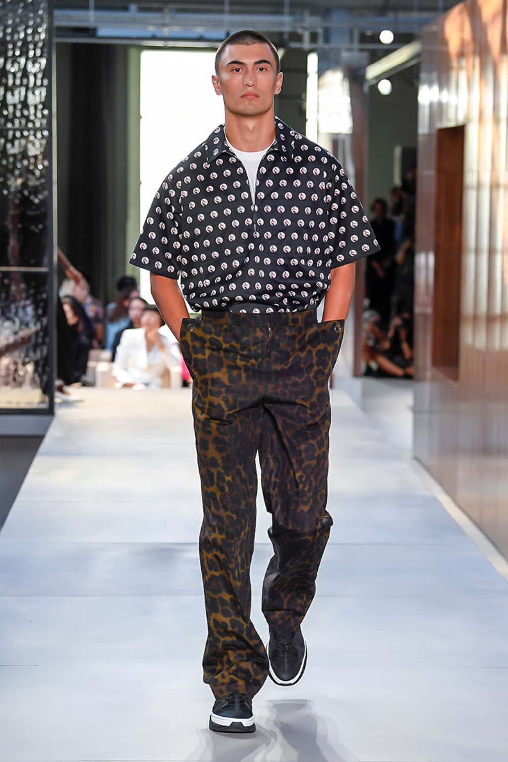 Male Runway Model Wearing Brown Leopard Print Pants and Black Short Sleeve Shirt with White Polka Dots-Burberry Men's Collection