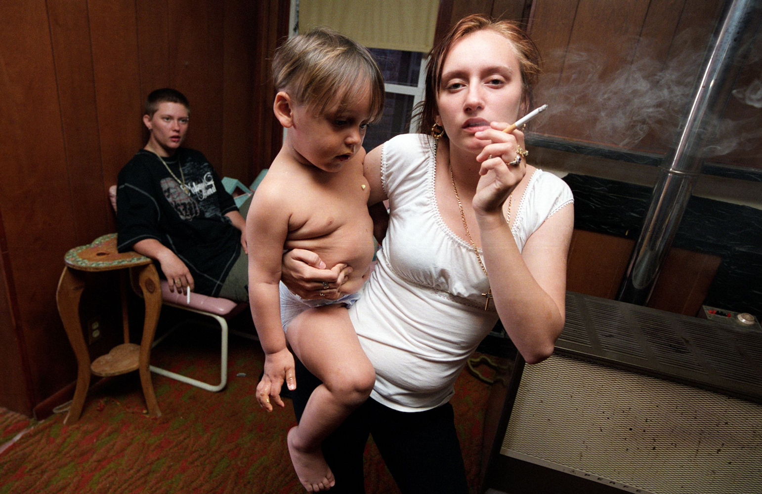 Young woman smoking and holding a baby