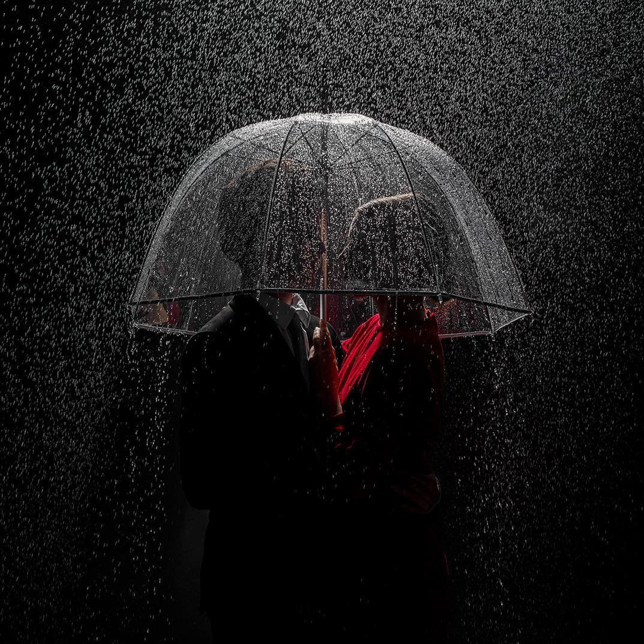 artistic image of couple under an umbrella in the rain at night