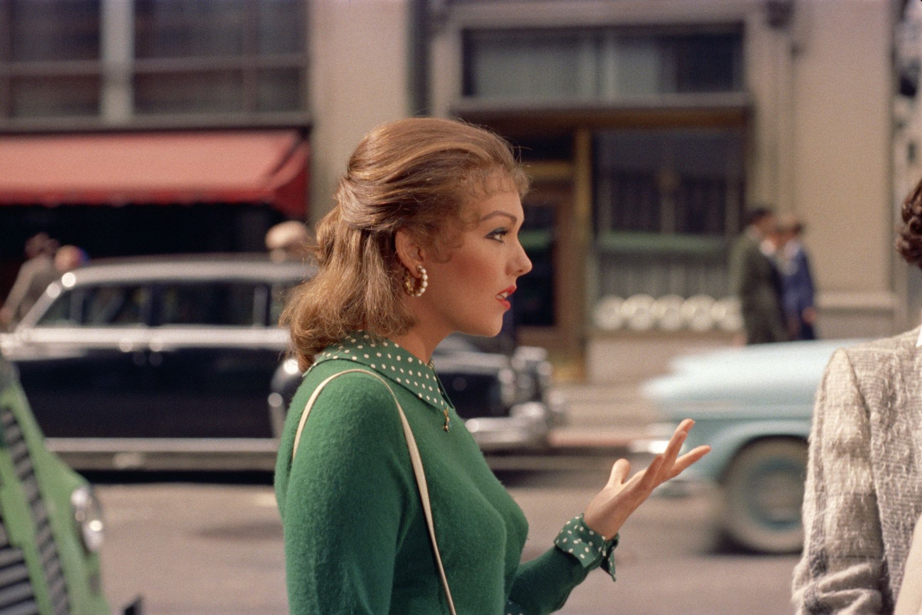 Brunette in a green sweater, profile view on a city street