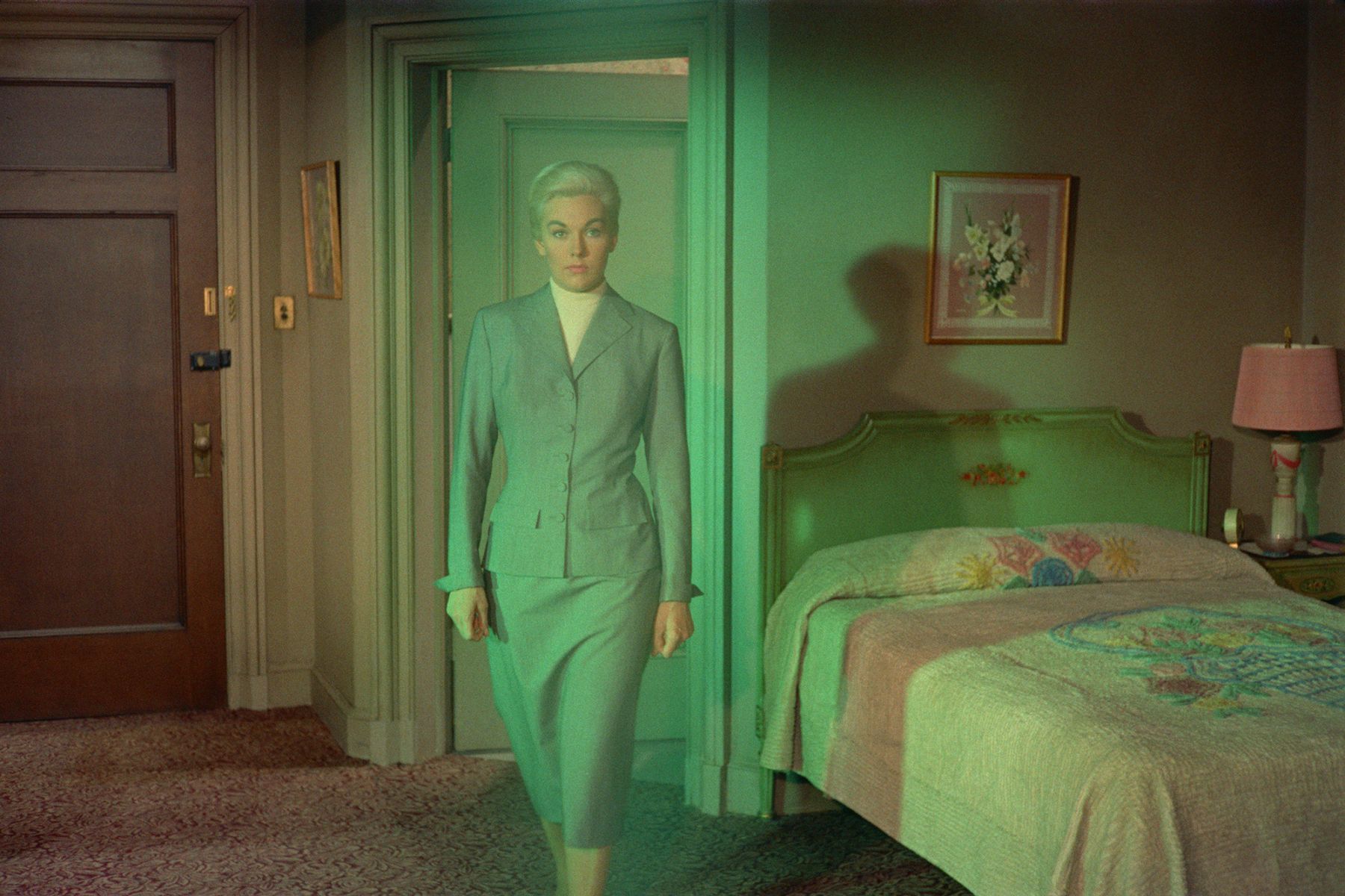 apparition of a woman in a skirt suit walks through a bedroom