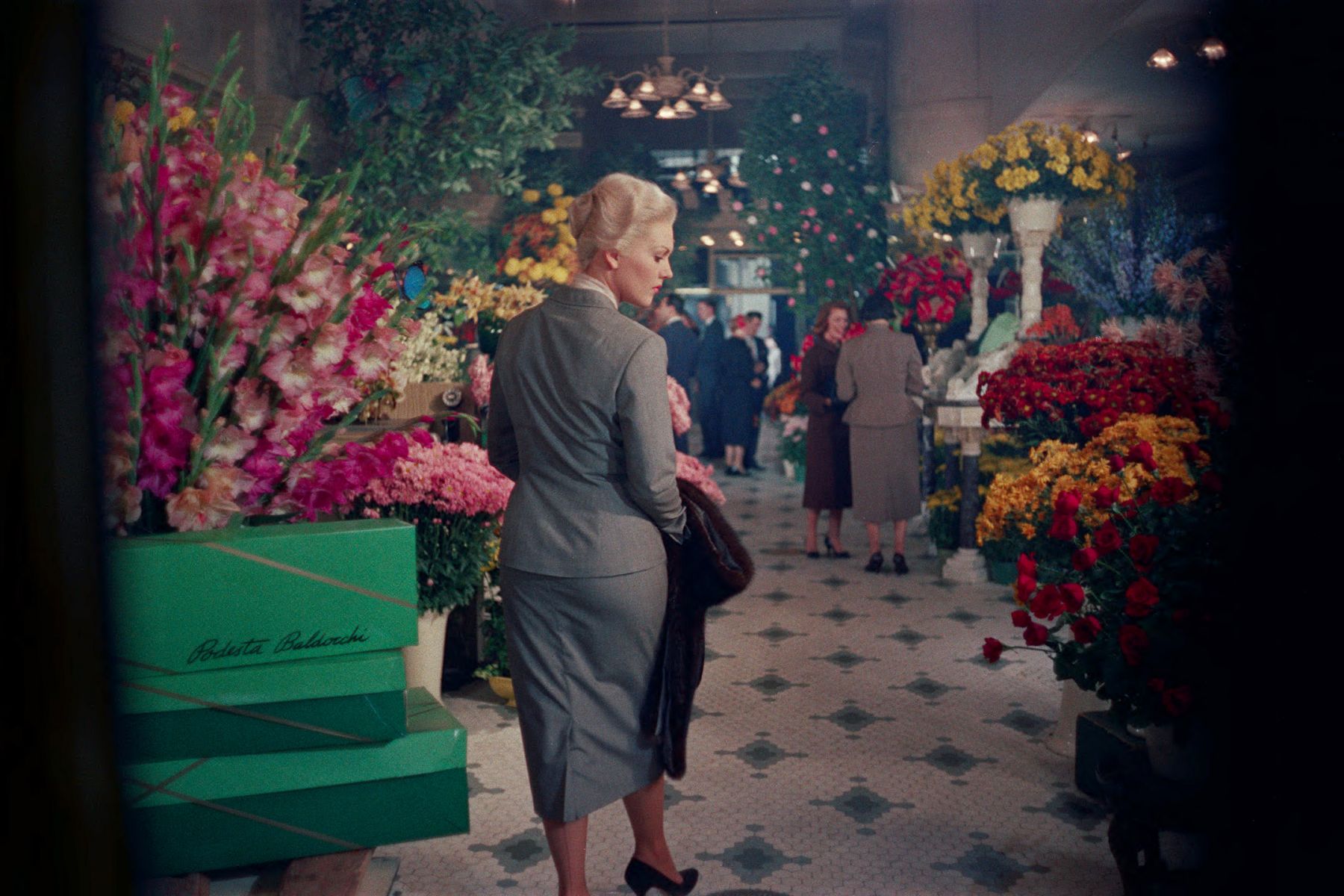 Woman in skirt suit walking through a flower shop