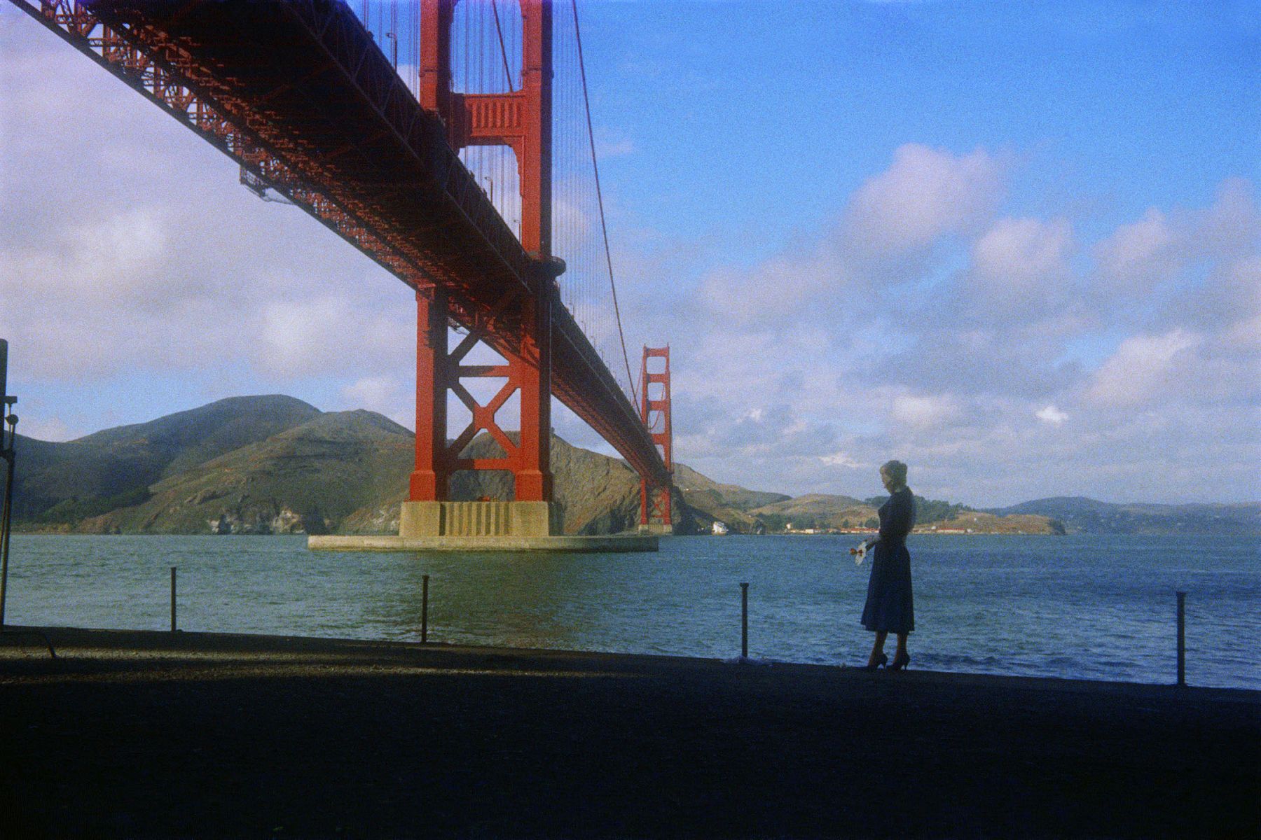 woman in Vertigo stands under the Golden Gate Bridge in California