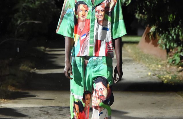 Pyer Moss Runway Model Wearing a green top and bottom printed with African faces of a boy and a man