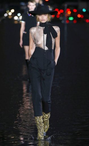 sexiest-womenswear designer of the year-YSL-2019-photo of runway model wearing hat, see through top, high waisted pants, long bow and lizard skin boots