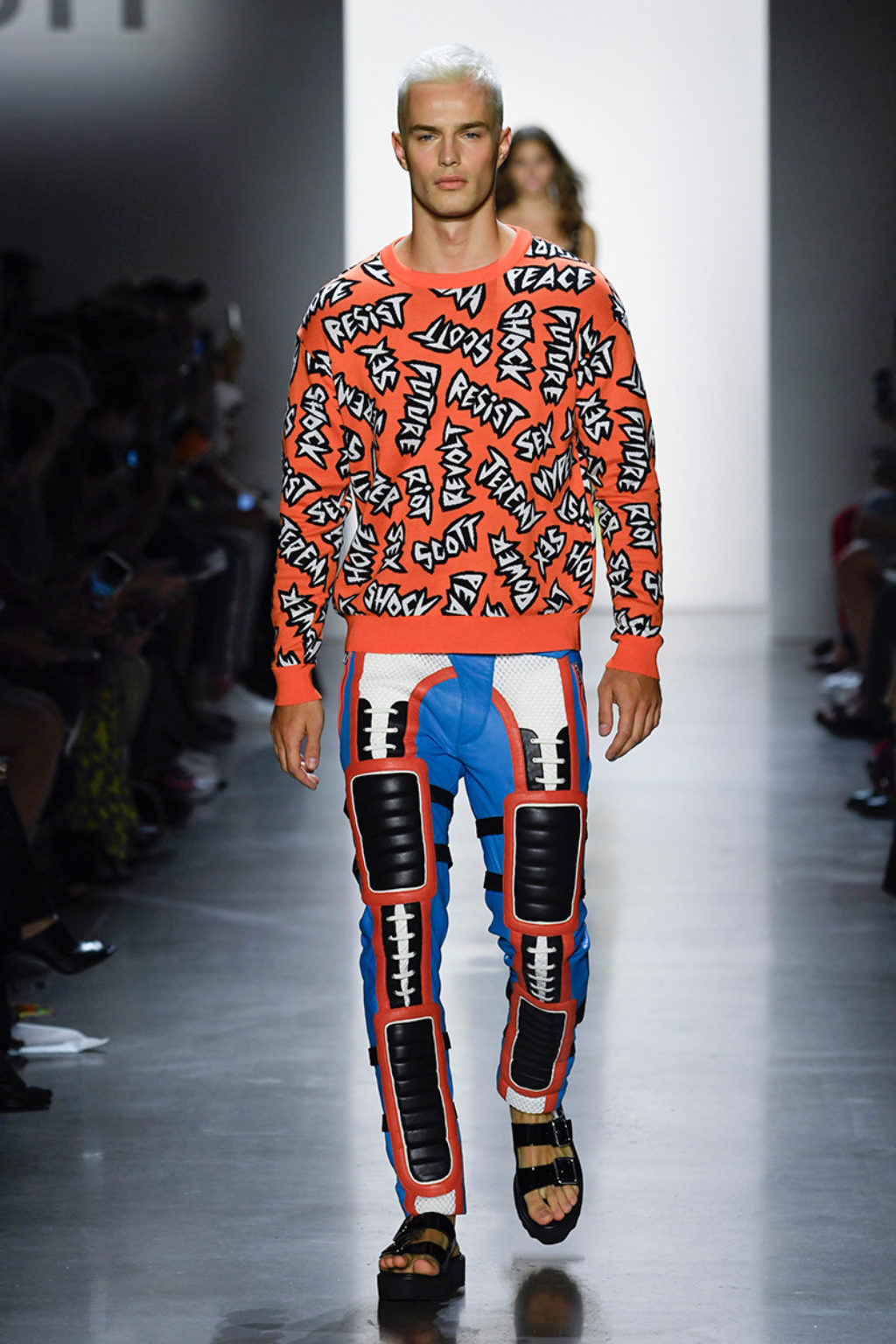 Jeremy-Scott-SS19 Male Runway Model Wearing Orange top with printed words-Resist-Scottfy1