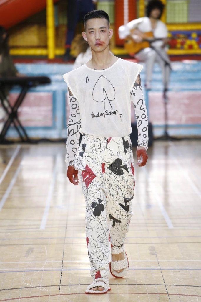 SS-2018-Vivienne-Westwood-Runway Model Wearing a White T-Shirt printed with hand drawn card suits, pants and sleeves with comical sleeves