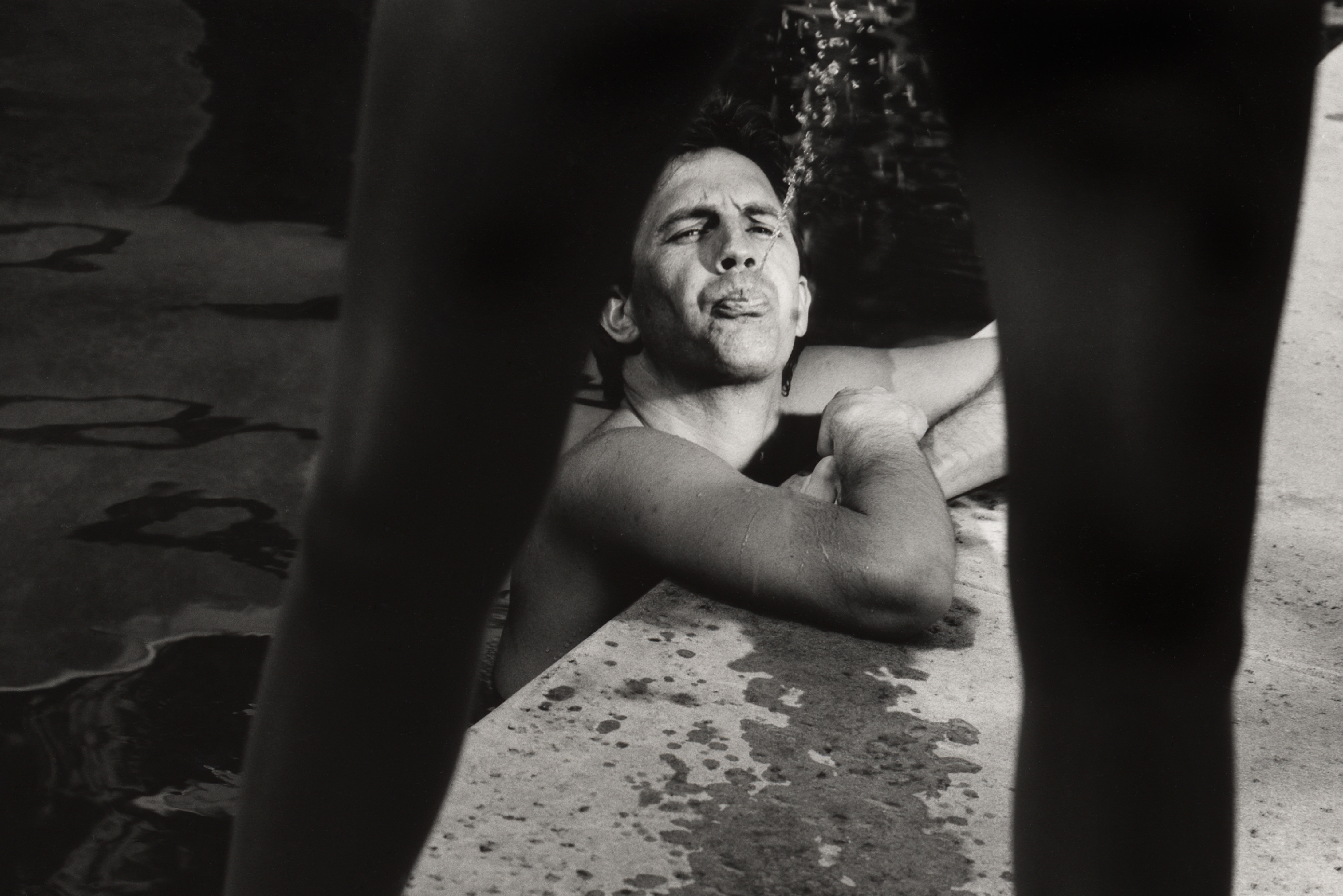 man in a pool spitting water, by greg gorman