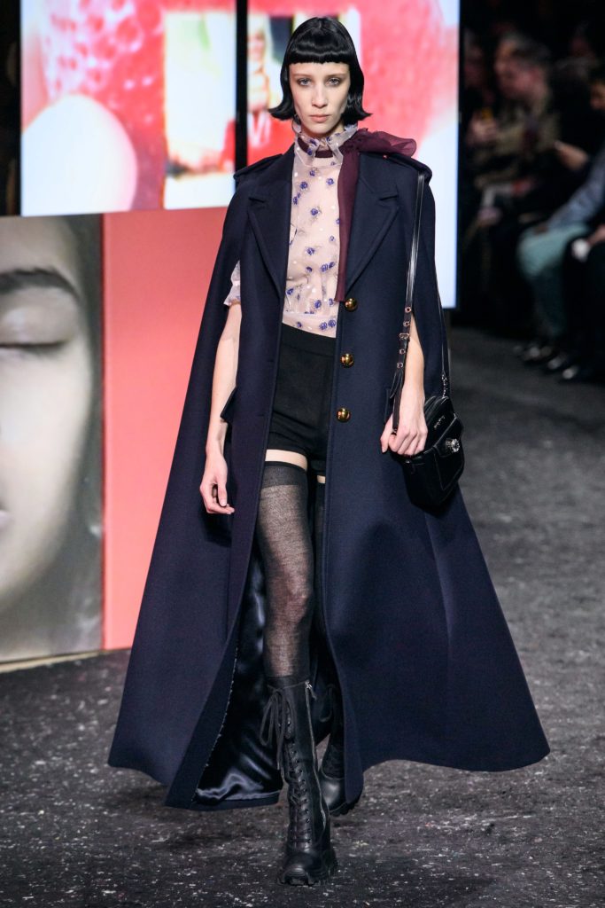 MIU MIU Fall 2019 Runway Model Wearing Military Inspired Navy Long Cape with black mini skirt and black lace up boots