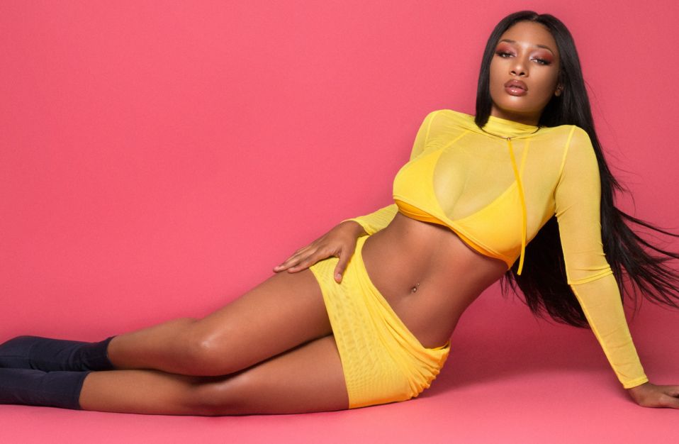 Megan Thee Stallion in a provocative pose wearing sexy yellow see through top and mini dress