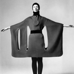 Pierre Cardin Model Holding Her Arms Out to Show a Wide Horizontal Dress form fitting at the body and with long thin vertical circles running below her armpits and Beatle boots