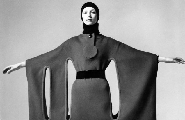 Pierre Cardin Model Holding Her Arms Out to Show a Wide Horizontal Dress form fitting at the body and with long thin vertical circles running below her armpits and Beatle boots