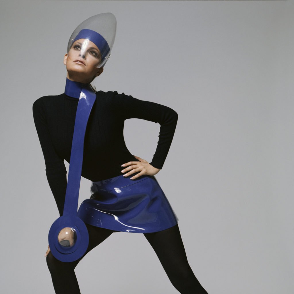 Pierre Cardin Model Wearing Back to the Future Looking Plastic Mask-Purple Patent leather mini skirt over a black cat suit