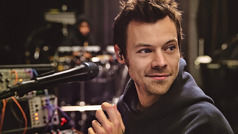 Harry Styles standing in front of microphone
