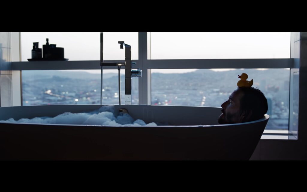 Keanu Reeves in a bathtub with rubber duck on his head in Matrix Resurrections