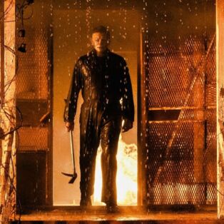 HALLOWEEN KILLS EVIL MAN IN THE DOOR FRAME OF A HOUSE ON FIRE WITH AN AX