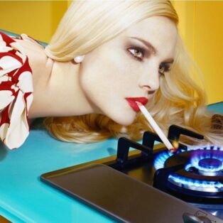 Miles Aldridge Image of Woman Lighting Her Cigarette on a stove burner flame