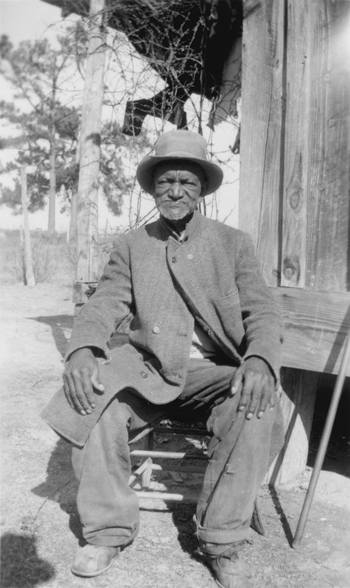West Brady Ex Slave Sitting In front of his Slave Cabin