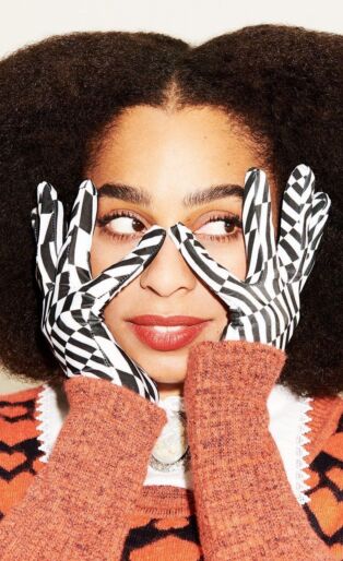 Celeste with graphic pattern gloves touching the sides of her face