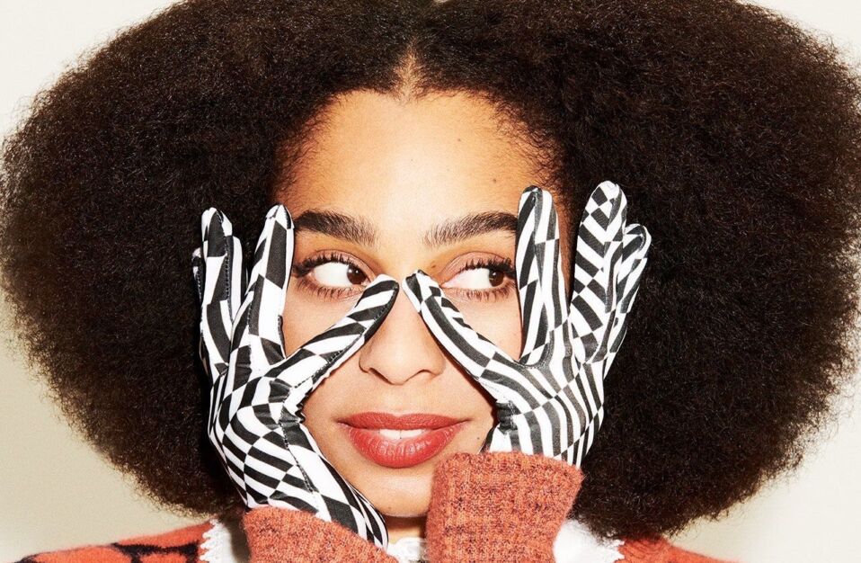 Celeste with graphic pattern gloves touching the sides of her face