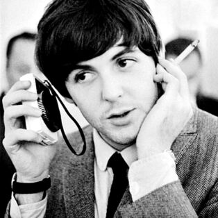Paul McCartney Listening to a Radio With Cigarette in Hand in the 1960s