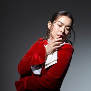 Mitski in Red Velvet Jacket Lookin to her side