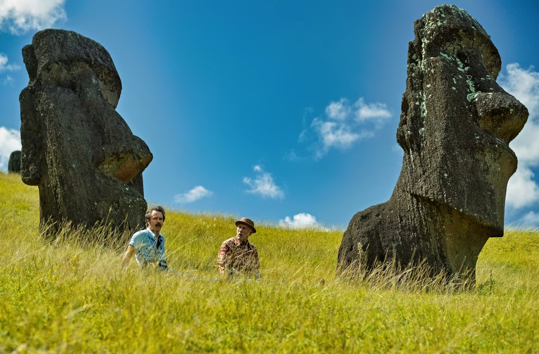Sam Rockwell, John Malkovich standing beside Easter Island statues